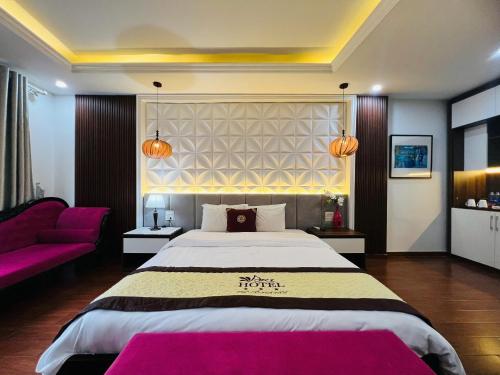 a bedroom with a large bed and a purple couch at Art Hotel Ha Noi in Hanoi
