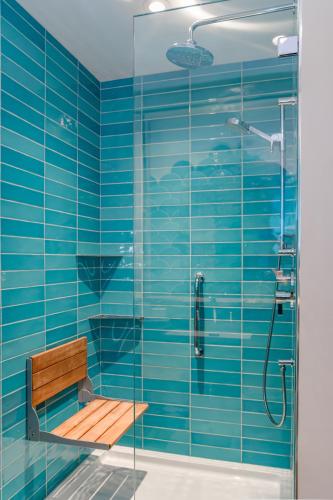 a blue tiled bathroom with a bench and a shower at Sungate on Salt Spring - Luxurious Suite with Cedar Hot Tub & View in Salt Spring Island