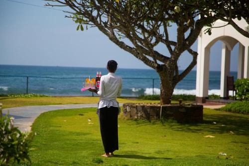 a man standing in the grass holding a tray of drinks at Hotel Lanka Super Corals in Hikkaduwa