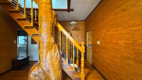 a room with a wooden staircase with a tree in the middle at Guesthouse YUFU in Yufuin