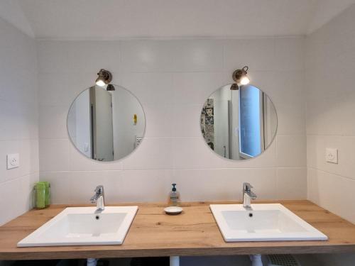 deux lavabos dans une salle de bain avec deux miroirs dans l'établissement Maison moderne 6 pers, plage et Internet à 900m, animaux acceptés - FR-1-775-4, à Le Tour-du-Parc
