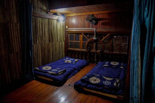two beds in a room with wooden walls at GoHaGiang in Ha Giang