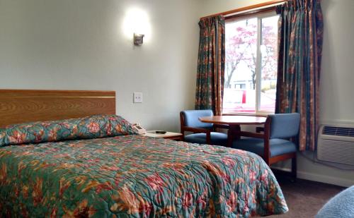 ein Hotelzimmer mit einem Bett, einem Tisch und einem Fenster in der Unterkunft Snooz Inn in Wilsonville