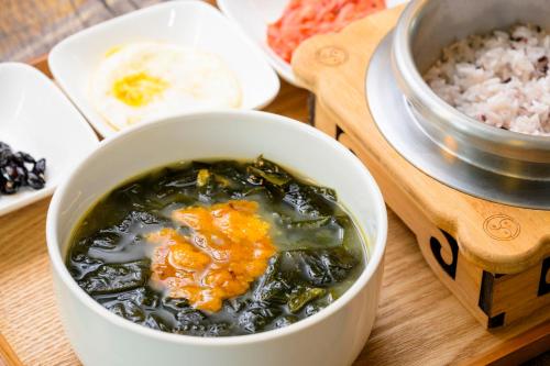eine Schüssel Suppe und Reis auf einem Tisch in der Unterkunft Jeju M Resort in Seogwipo