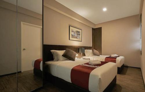 a hotel room with two beds and a mirror at Maritime Suites Penang in Jelutong