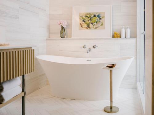 a white bath tub in a bathroom with a sink at Regent Santa Monica Beach in Los Angeles