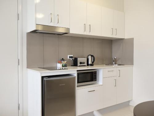 a kitchen with white cabinets and a stainless steel appliance at Quest Breakfast Creek in Brisbane