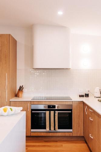 a kitchen with wooden cabinets and a black oven at Blanca Beach House in Weymouth
