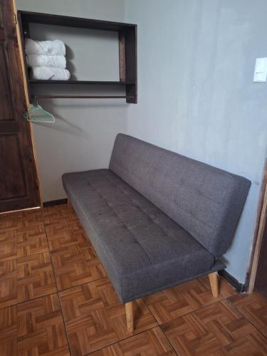 a gray couch sitting in a corner of a room at Anchia - Hostel in Alajuela City