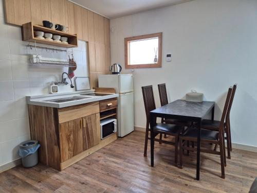 a kitchen with a table and a sink and a refrigerator at Jeju Soroan Pension in Seogwipo