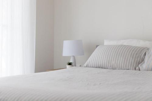 a bedroom with a white bed and a lamp at Rockpool Cape Paterson in Cape Paterson