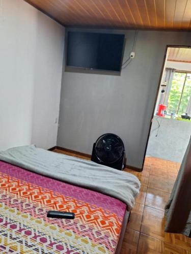 a bedroom with a bed with a tv on the wall at Anchia - Hostel in Alajuela City