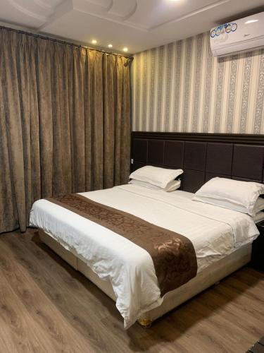 a bedroom with a large bed with white sheets at Oroub El Forssan in Buraydah