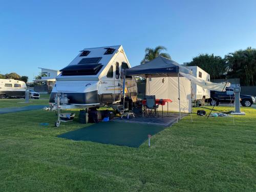 an rv parked in a field with a tent at Nobby Beach Holiday Village in Gold Coast