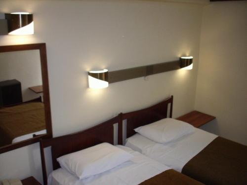 een slaapkamer met 2 bedden en een spiegel en verlichting bij Claridge Hotel in Athene
