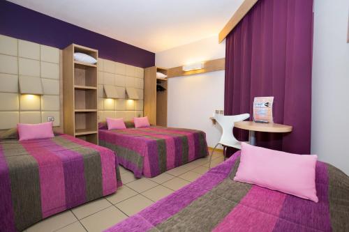 a hotel room with two beds and purple curtains at Hotel Espace Cite in Carcassonne
