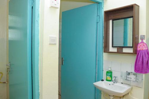 a bathroom with a blue door and a sink at Adorable Homely Stay in Nakuru