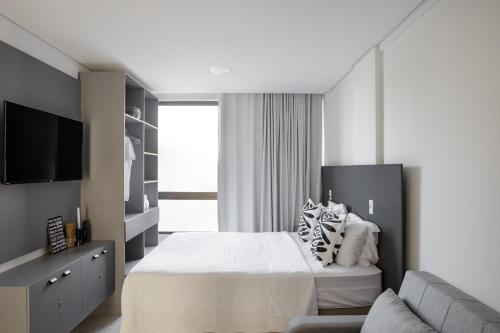 a bedroom with a bed and a couch at Feel Home - Flat Romântico com Piscina no Rooftop in Cabedelo