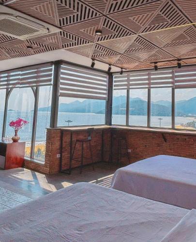 a room with two beds and a table and windows at Ly Ky Hotel in Quy Nhon