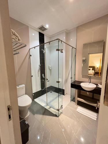 a bathroom with a shower and a toilet and a sink at Gets Hotel in Malang
