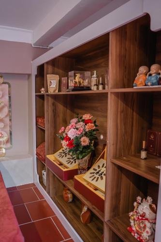 a book shelf with books and a bouquet of flowers at D Banlieue Homestay And Coffee TP Kon Tum in Kon Tum