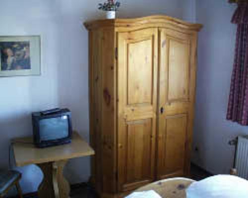 a bedroom with a wooden cabinet and a television at Hotel Restaurant Schrotmühle in Scheinfeld