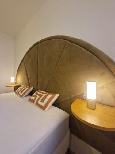a bed with a wooden headboard and a table with a lamp at Luminea - Apt T3 avec parking souterrain - Aéroport Blagnac, MEET et tram in Blagnac