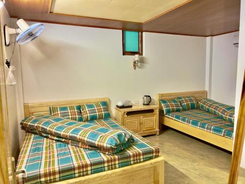 a room with two beds and a table at Homestay duy mạnh gần suối nước khoáng nóng trạm tấu in Cham Ta Lao