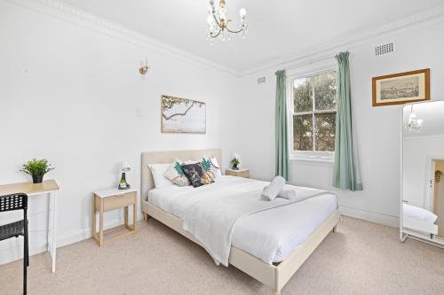 a white bedroom with a bed and a window at Rustic Queen Room - Seconds to Stores & Eateries - Shared Bathroom in Sydney