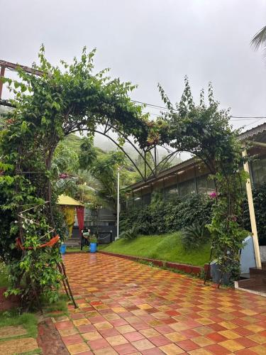 an archway in a courtyard with trees and plants at Madhura Agro Tourism in Wai