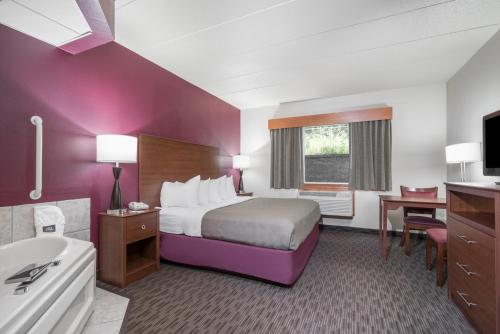 a hotel room with a bed and a tub and a sink at AmericInn by Wyndham Baldwin in Baldwin