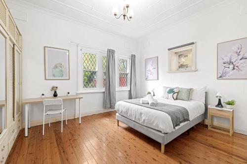 a white bedroom with a bed and a desk at Quaint Double Room - Seconds to Shops & Eateries - Shared Bathroom in Sydney