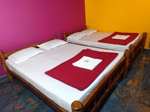 two beds in a room with red towels on them at Waves End Beach Front Stay in Gokarn