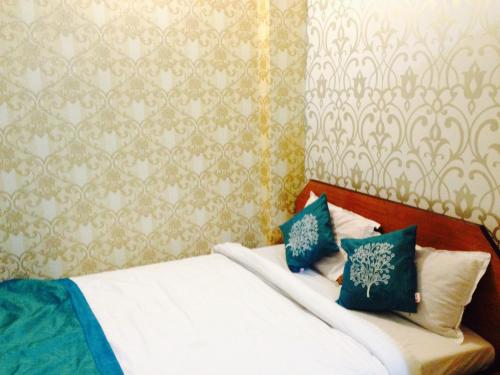 a bedroom with a bed with blue and white pillows at Hotel Bengal in Kolkata