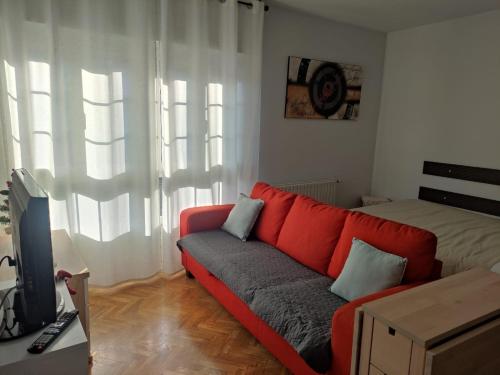 a living room with a red couch and a bed at Rincón de la Habana in Siero