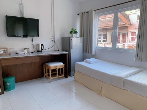 a bedroom with a refrigerator and a window and a tv at Sunshine Guest House in Hua Hin
