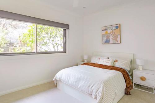 a white bedroom with a bed and a window at Newport Oases in Newport