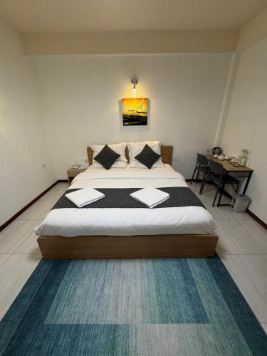 a bedroom with a large bed and a table at Eydhafushi Home Stay Residence in Eydhafushi