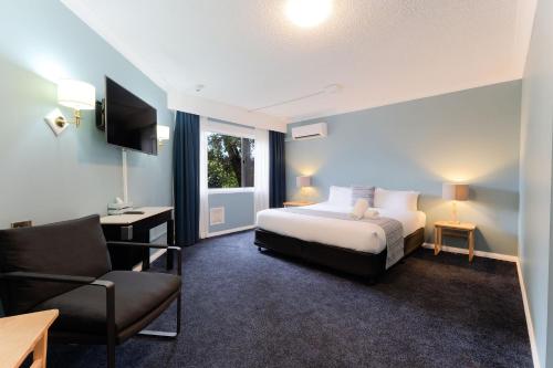 a hotel room with a bed and a chair at Leura Gardens Resort in Leura