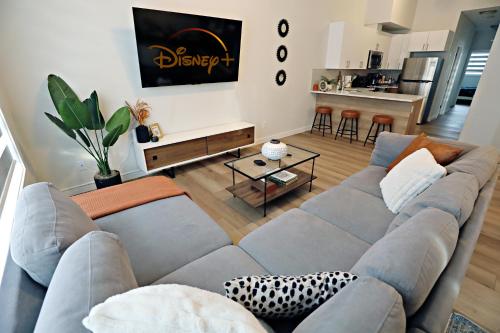 a living room with a gray couch and a kitchen at Downtown 3 Queen Beds, AC, Double Garage, Disney in Edmonton