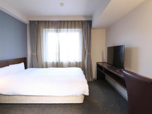 a hotel room with a bed and a television at Dormy Inn Wakkanai in Wakkanai