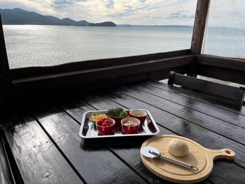 a tray of food sitting on a table next to the water at ITOSHIMA SDGs Village Chikyu MIRAI -海の大パノラマ-全室オーシャンビューのドームテント in Itoshima