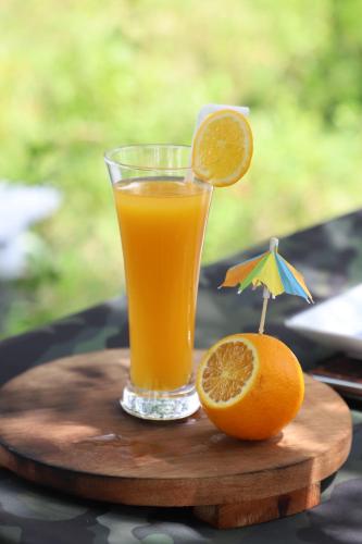 a glass of orange juice and an orange cut in half at Gal Oya Camping in Inginiyagala
