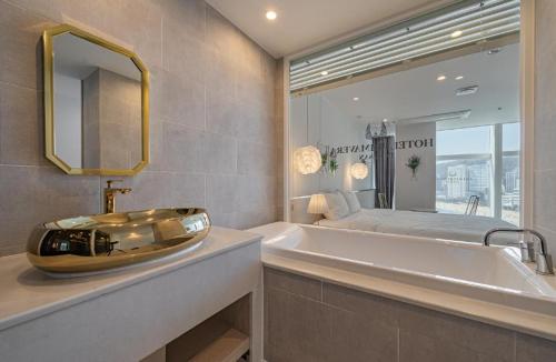 a bathroom with a sink and a tub and a bed at Gwangalli Hotel primavera in Busan in Busan