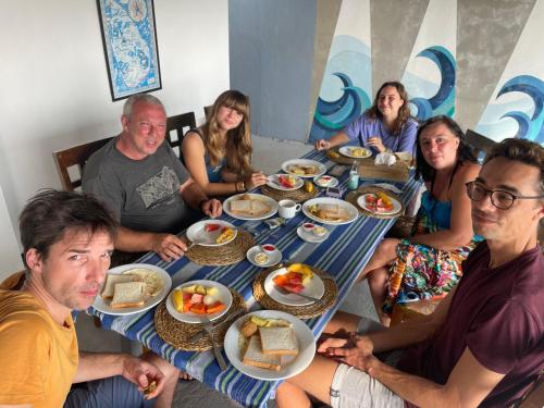 a group of people sitting around a table eating food at Kenno's Korner in Weligama