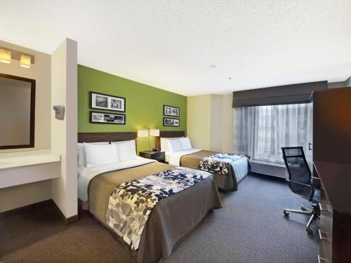 a hotel room with two beds and a flat screen tv at Baymont by Wyndham Fort Collins in Fort Collins