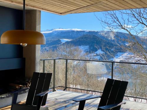 a balcony with a table and chairs and a view at L'Avancée Chalet contemporain au coeur du Sancy AUVERGNE in Murat-le-Quaire