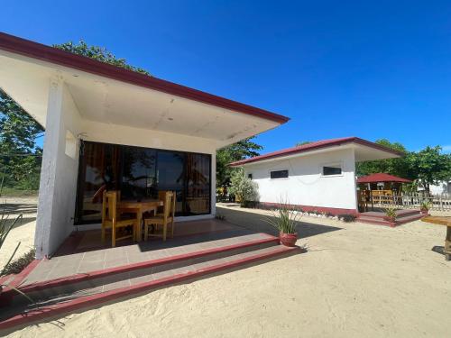 a small white house with a table and chairs at Bolo Hills Beach Club And Residence in Alaminos