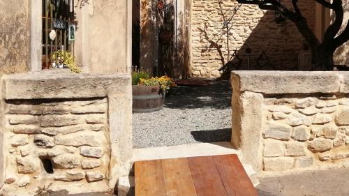 a stone wall and a wooden table in front of a building at Les Gîtes sous l' Olivier en Camargue in Vauvert