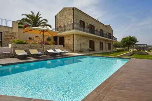 a villa with a swimming pool in front of a house at Casa al Castello in Cannizzara